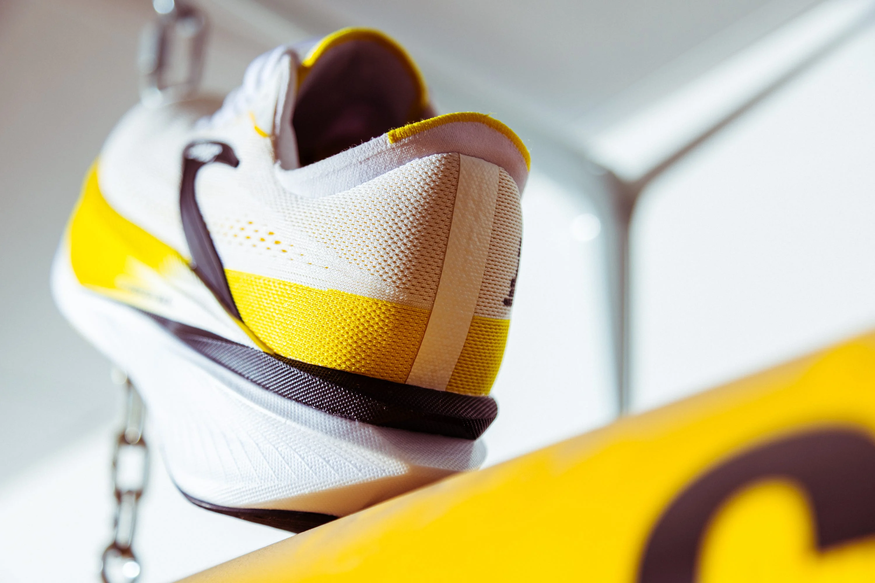 Close-up of a white and yellow athletic shoe with a textured surface.