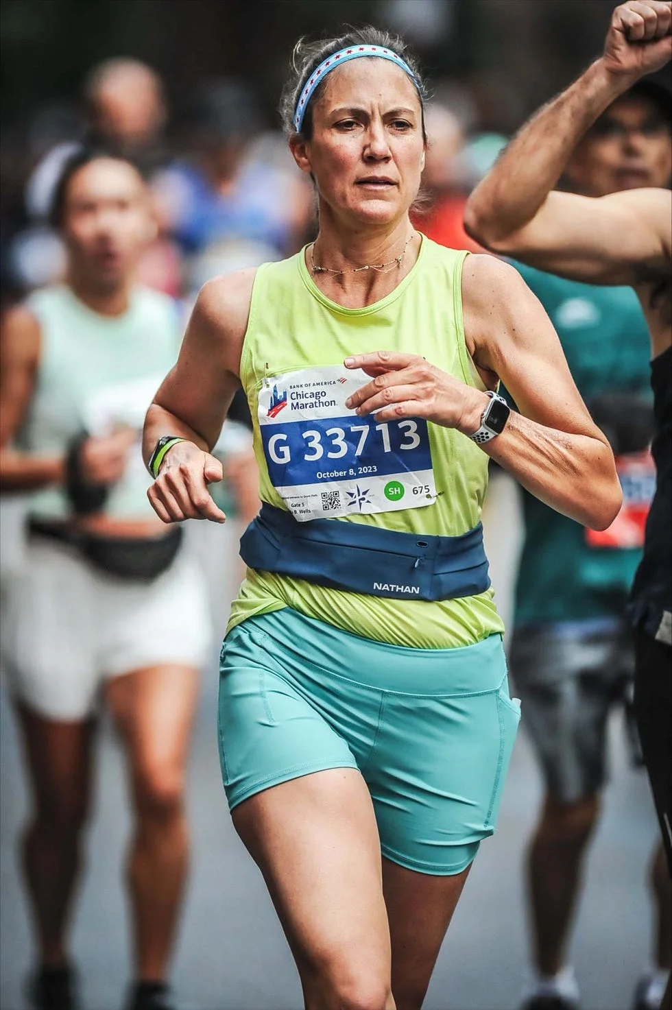 A runner participating in the Chicago Marathon, wearing a green tank top and shorts, focused on the race.