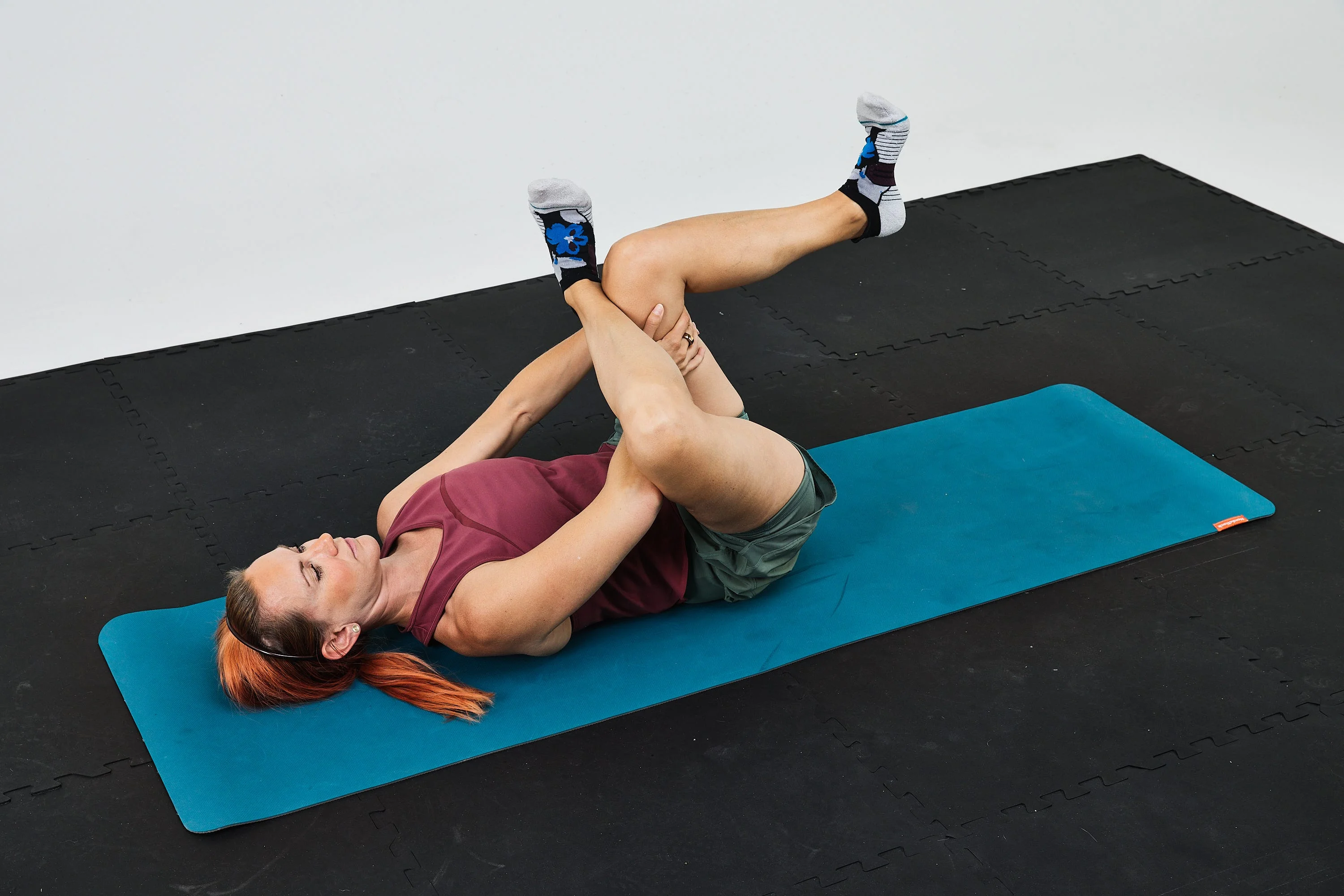 Woman performing a stretching exercise on a yoga mat in a fitness setting.