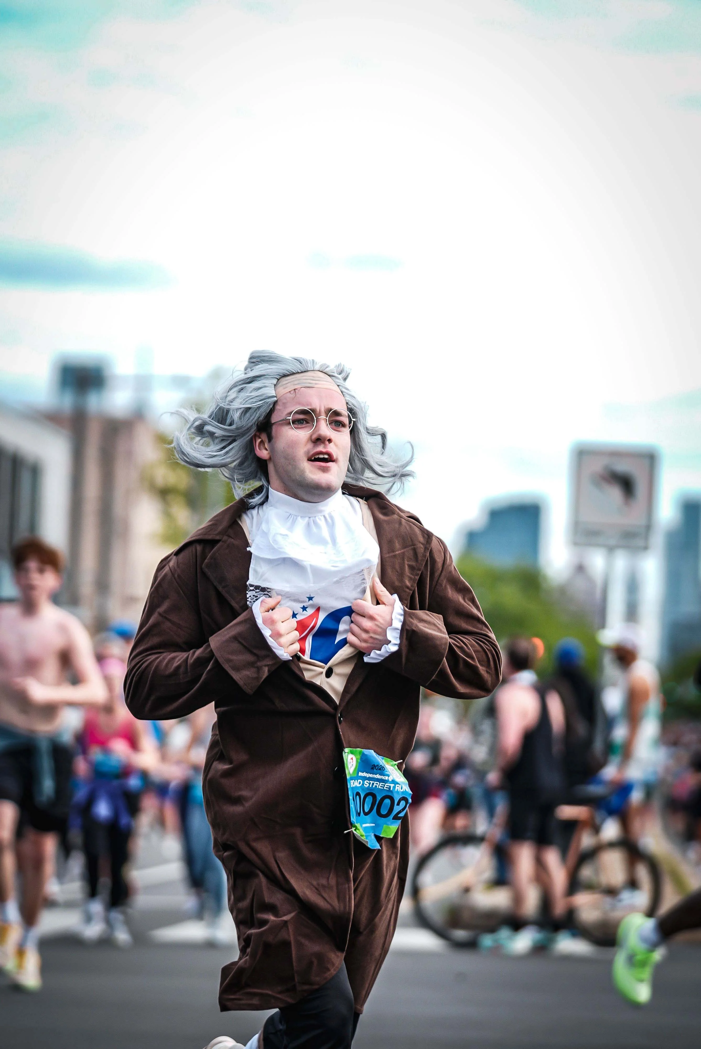 Runner dressed in historical attire with gray hair and glasses participates in a marathon event.