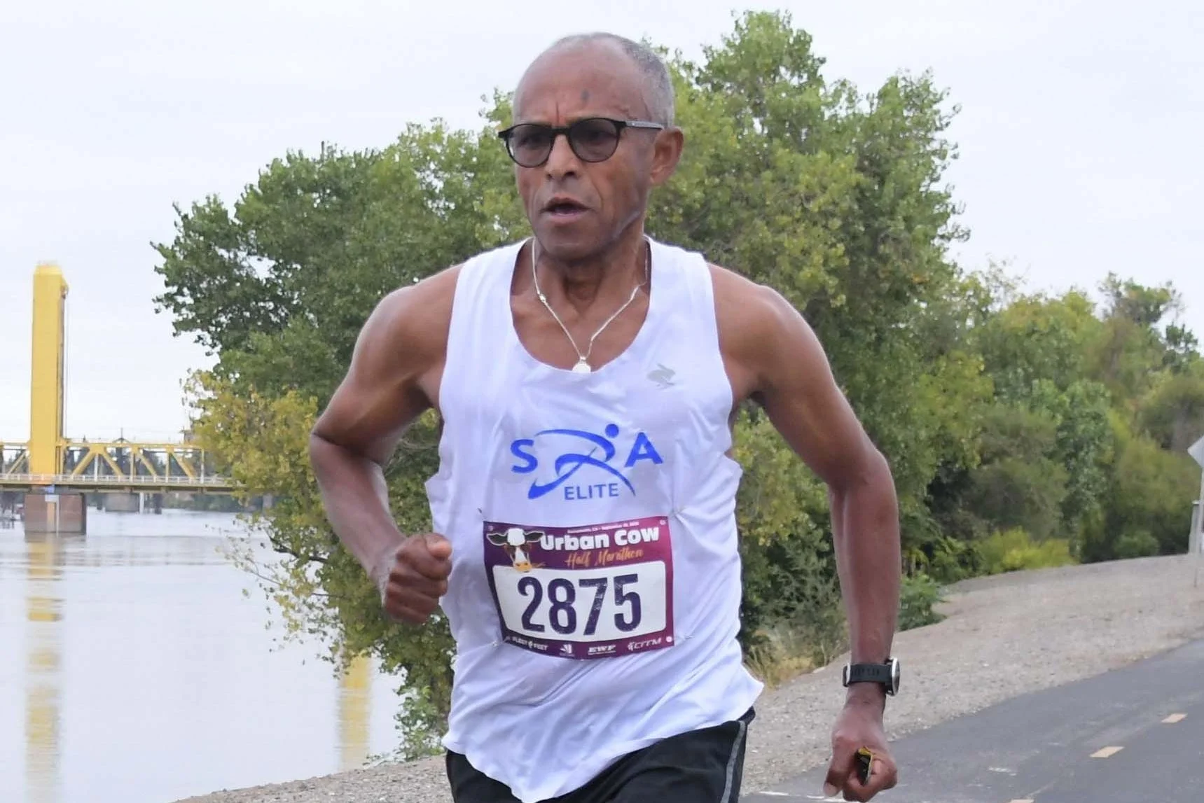 Runner in athletic gear competing in a half marathon along a scenic path by the water.