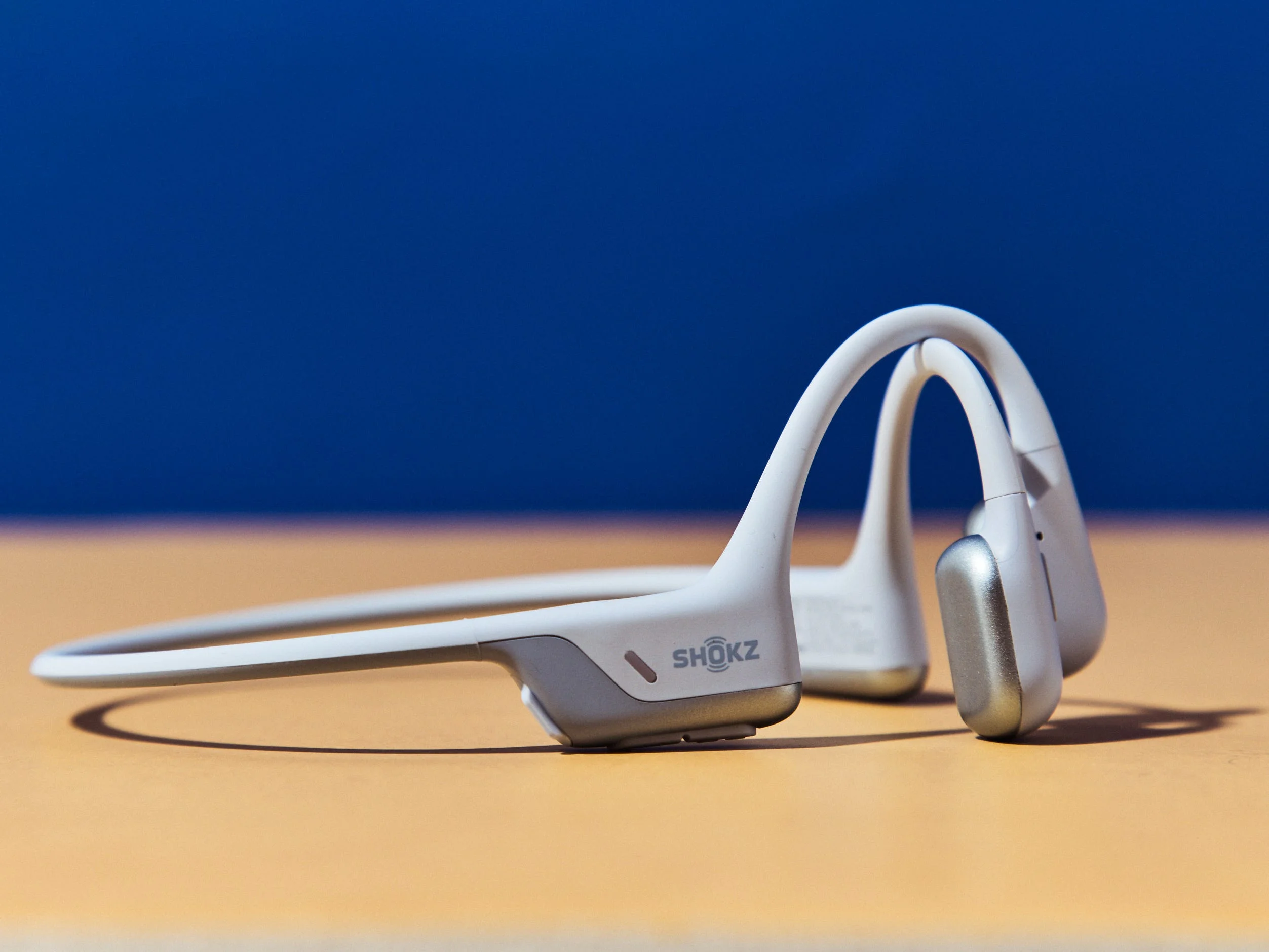 Lightweight bone conduction headphones on a surface with a blue background. Lightweight bone conduction headphones on a surface with a blue background.
