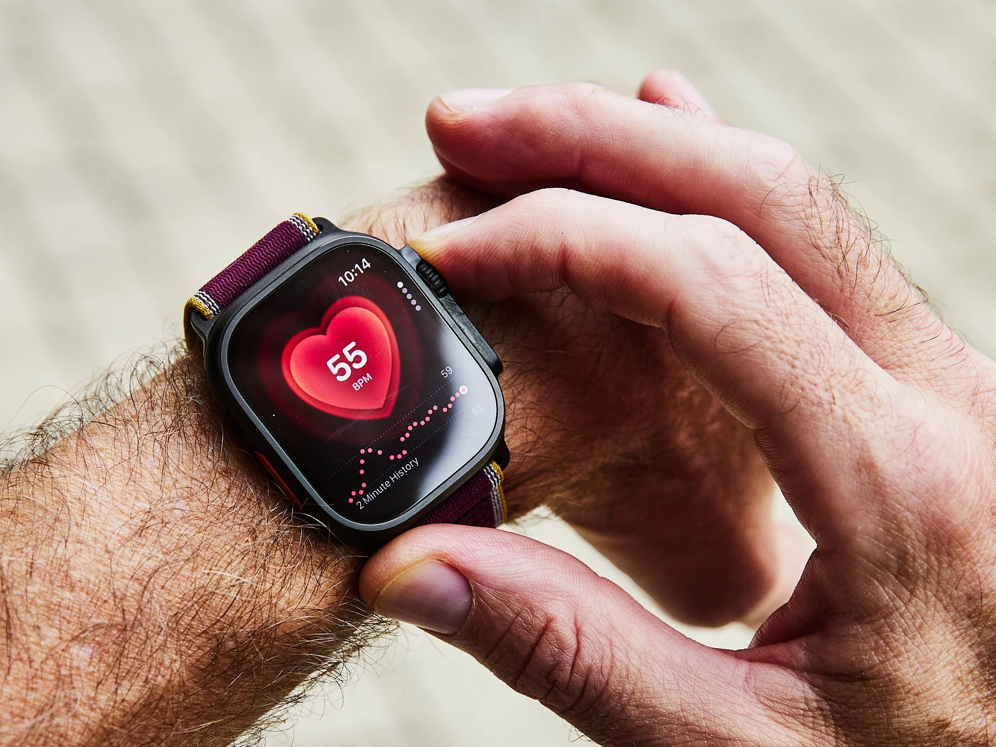 A person checking their heart rate on a smartwatch displaying a reading of 55 BPM.