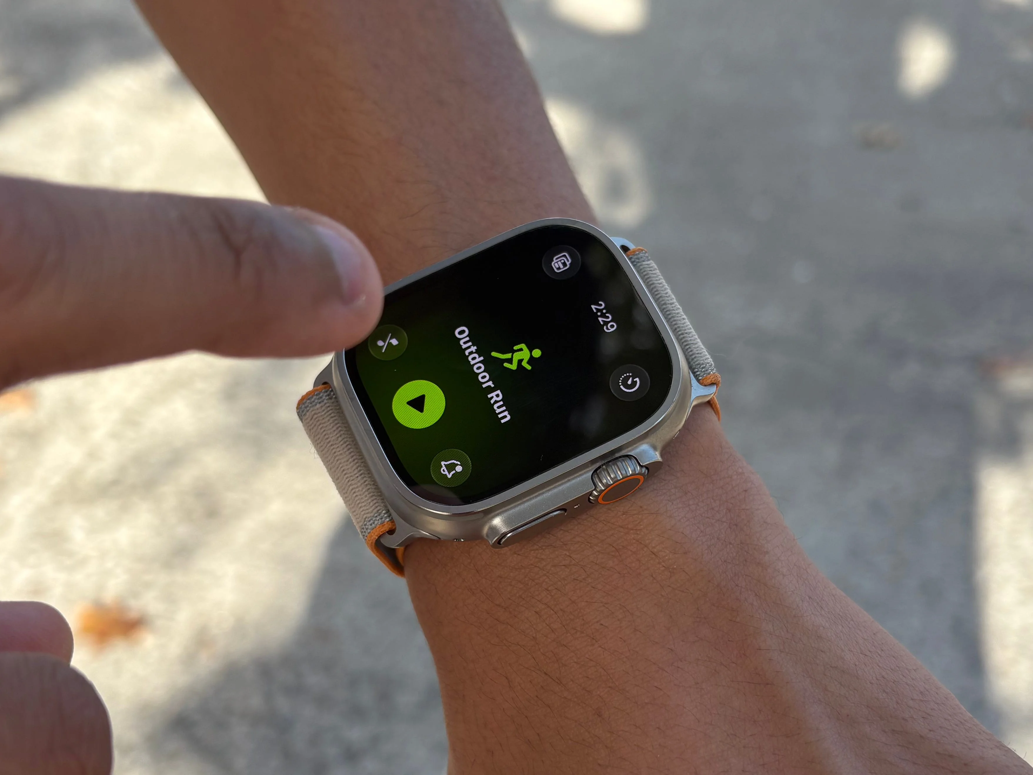 User tapping a apple watch ultra 4 displaying an outdoor run activity screen.