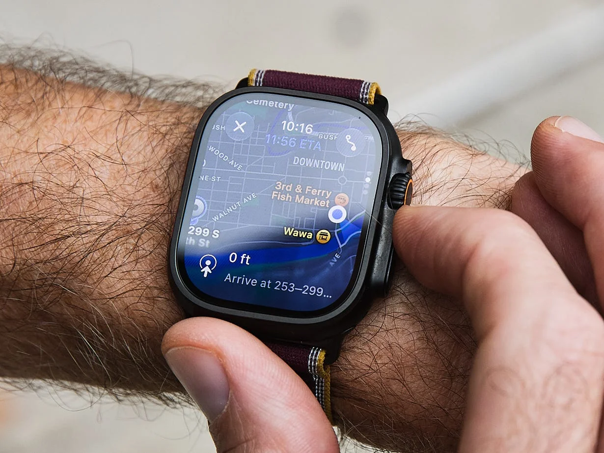 Smartwatch displaying navigation information on a person's wrist while they interact with the touchscreen.