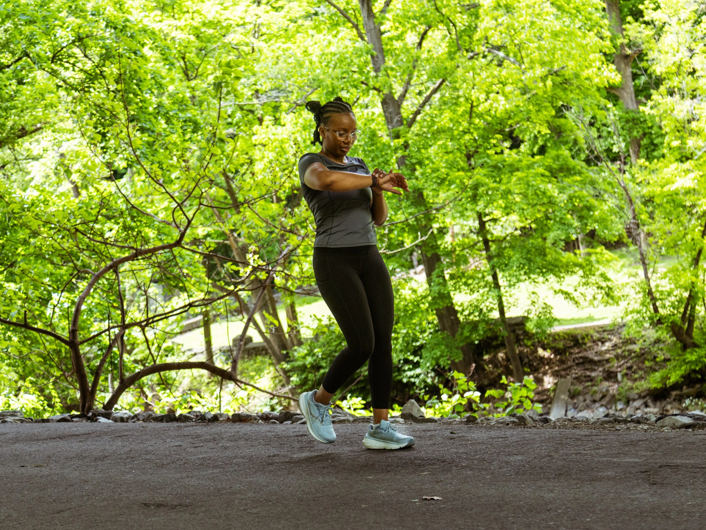 Person checking a smartwatch while walking along a tree-lined path. Person checking a smartwatch while walking along a tree-lined path.